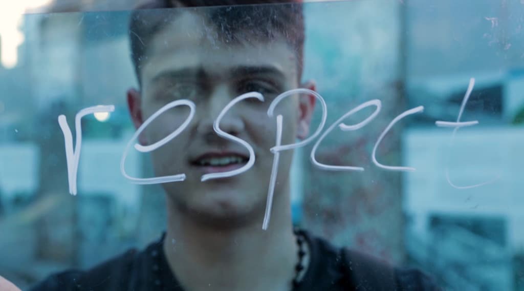 Image of young man behind transparent board with the word respect written on it